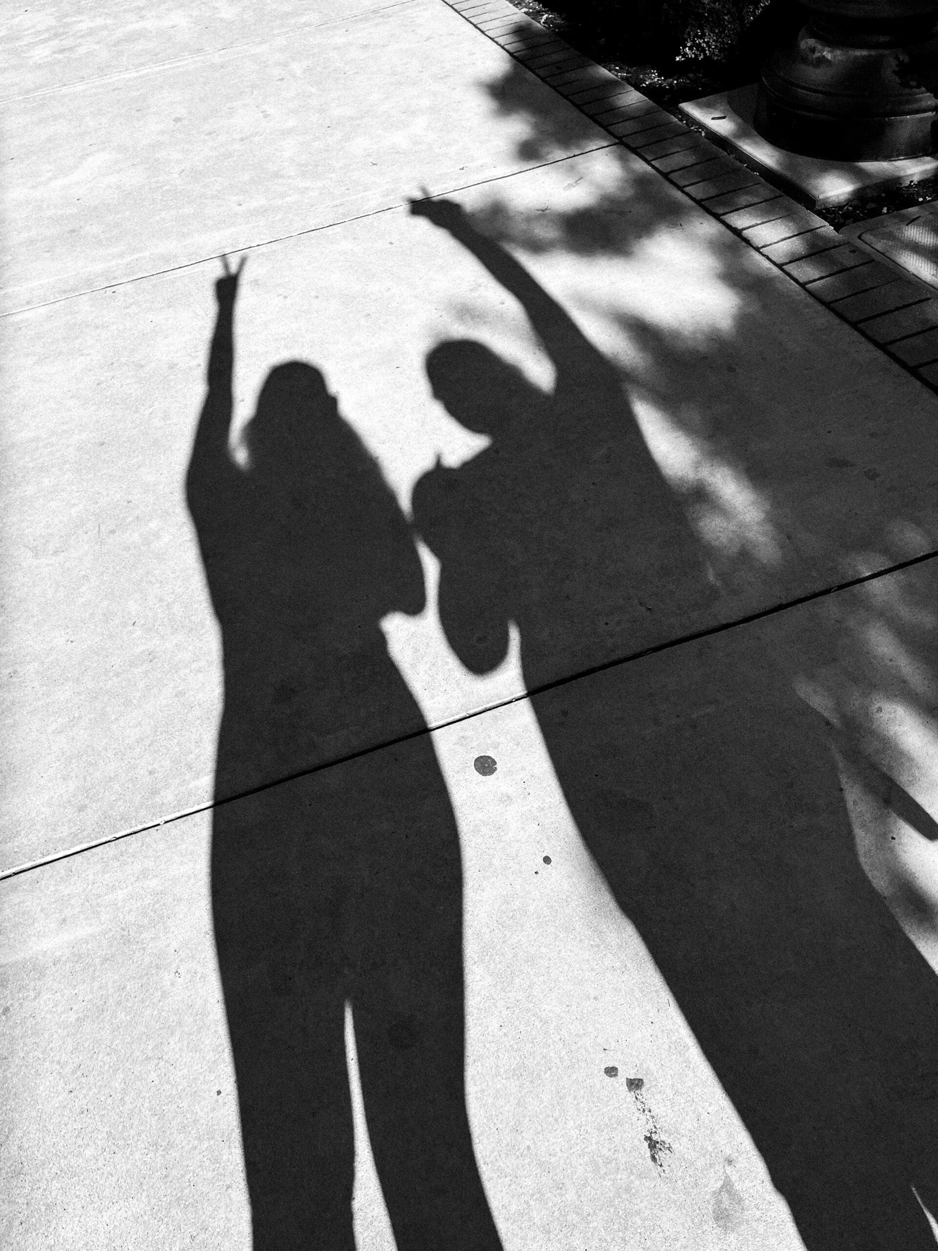 two friends walking and taking a picture of their shadow