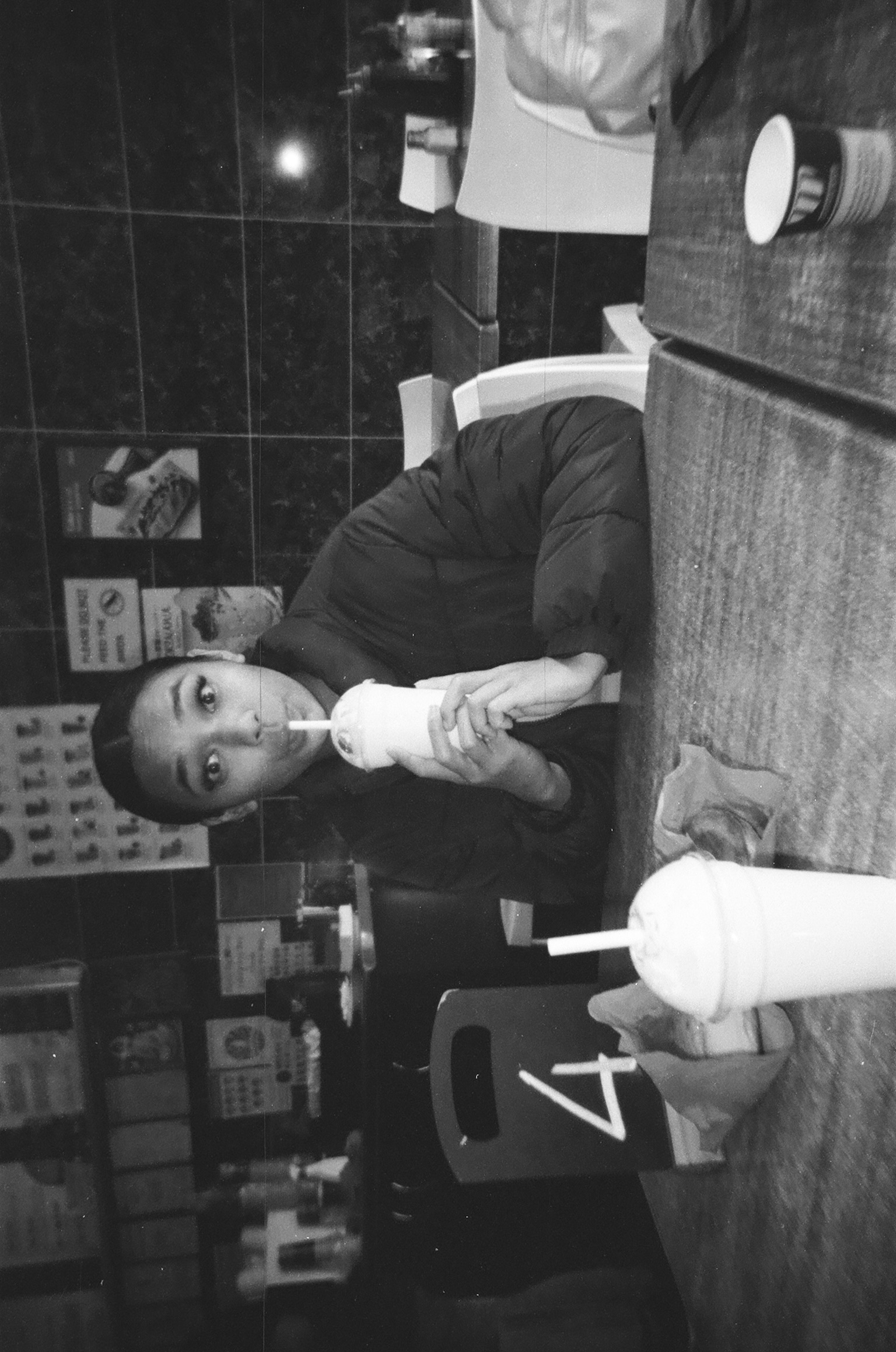 Black and white photo of a young girl drinking a smoothie through a straw, looking relaxed and thoughtful — a moment of quiet reflection on how to stay consecrated in a season of promise.