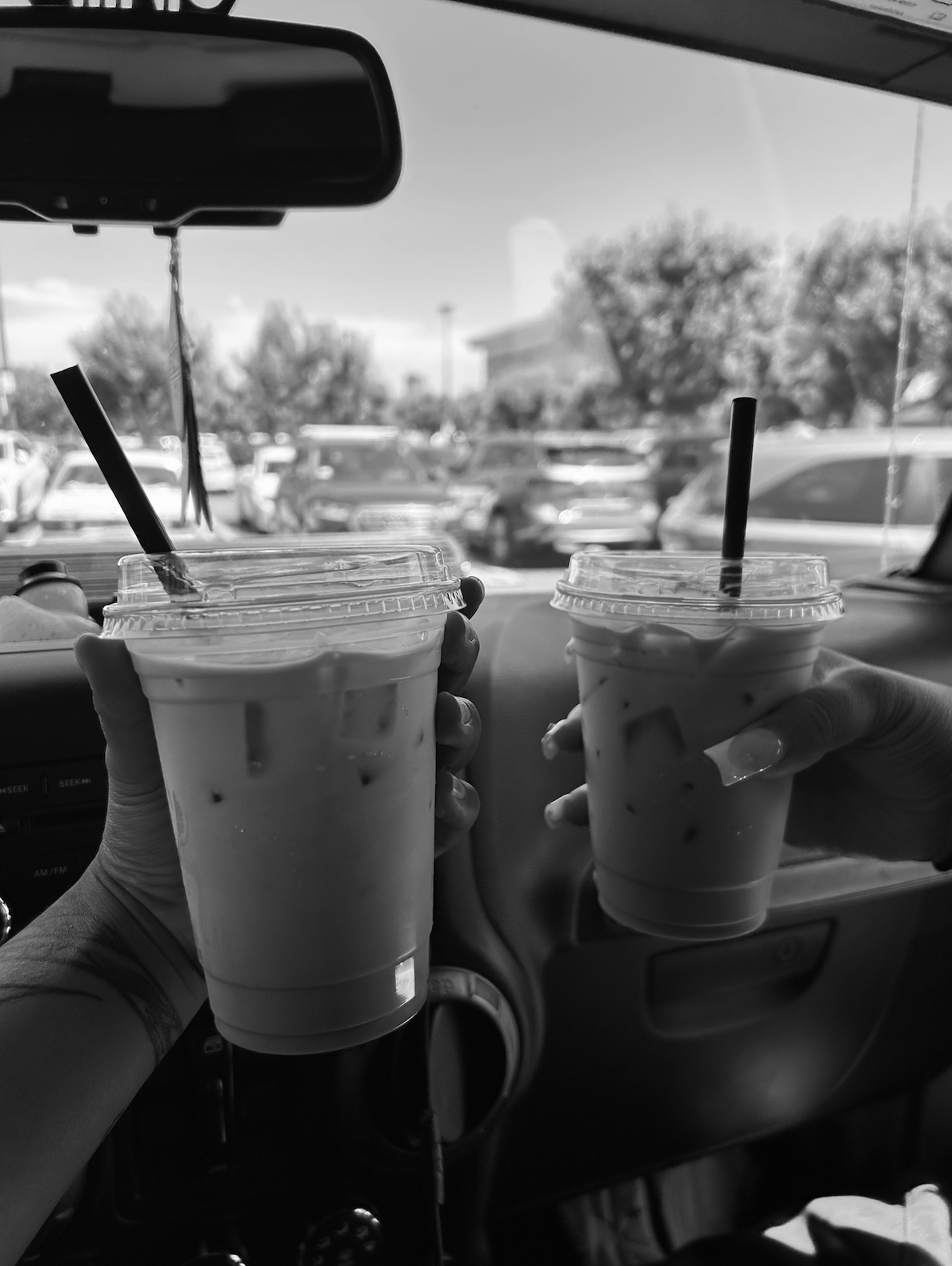 two coffees in a car being shown and held up in black and white